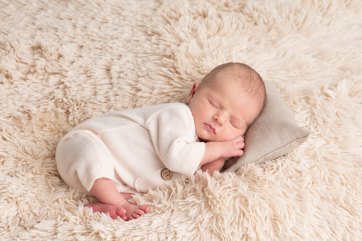 Photographe naissance Seine-et-Marne, nouveau-né endormi dans une corbeille en osier, pose artistique avec accessoires studio.